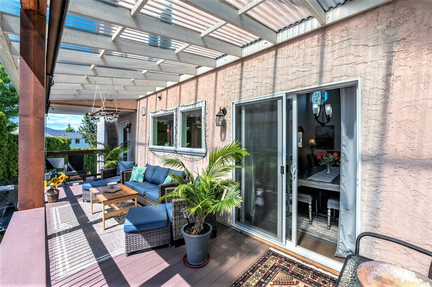 Un patio couvert avec des meubles d’extérieur, un coin repas et une porte-fenêtre coulissante donnant sur une pièce.