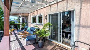 A covered patio with outdoor furniture, a dining area, and a sliding glass door leading to a room.