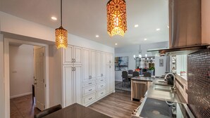 A modern kitchen with a dark countertop, white cabinetry, and a hanging light fixture.