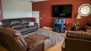 Una sala de estar con un sofá de cuero marrón, un televisor y un sistema de sonido.