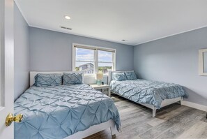 A bedroom with two beds, a window, and a door.