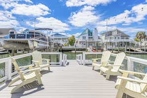 A wooden pier with white Adirondack chairs, a dock with boats, and houses with blue roofs. - Spring Break Sale! Just 2 min walk to Beach + Canalfront, Beach Esssentials (Holden Beach)