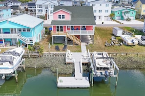 A waterfront property with a dock, a house with a balcony, and boats.