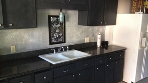 A kitchen with dark cabinets, a white sink, and a refrigerator. - Foresthill Getaway is located in town and close to many wedding sites. (Foresthill)