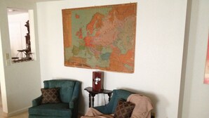 A living room with two teal armchairs, a small table, and a large vintage map on the wall. - Foresthill Getaway is located in town and close to many wedding sites. (Foresthill)
