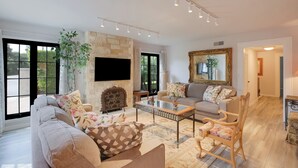 A spacious living room with a sofa, armchair, coffee table, and a fireplace. - Prime Montecito Beach Location (Montecito)
