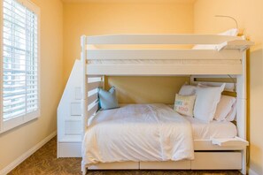 A bunk bed with a headboard, pillows, and a bedside table.