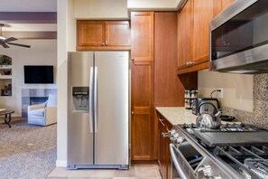 A kitchen with wooden cabinets, a stainless steel refrigerator, a gas stove, and a microwave.