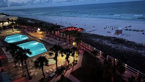 A beachside resort with two swimming pools, sun loungers, and a lifeguard tower.