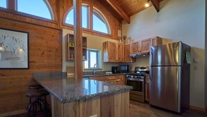 Una cocina con armarios de madera, encimera de granito, electrodomésticos de acero inoxidable y un ventanal amplio.