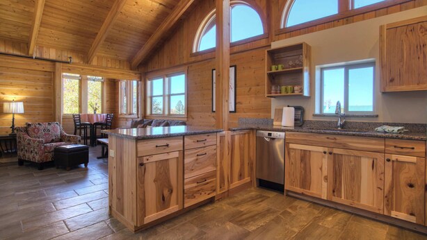 Una cocina amplia con armarios de madera, una isla central y ventanas grandes.