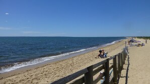 A beach with a wooden boardwalk, sandy beach, and the ocean.