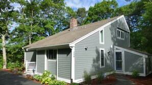 A two-story house with a front porch, a chimney, and a small attached garage.