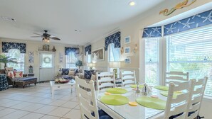 A dining area with a glass table, white chairs, and green placemats. - Private Pool, Small pets welcome, walk to beach, bikes and golf cart included (Destin)