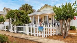 A single-story house with a white picket fence, a covered porch, and a small front yard with a tree and mulch. - Private Pool, Small pets welcome, walk to beach, bikes and golf cart included (Destin)