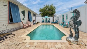 A swimming pool with a statue, lounge chairs, and a covered patio area. - Private Pool, Small pets welcome, walk to beach, bikes and golf cart included (Destin)