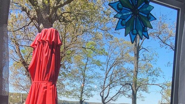 A view from a window overlooking a lake, with a red umbrella, wicker chairs, and a blue decorative item. - Lake front (Sunrise Beach)