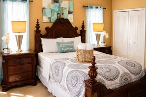 A neatly made bed with a patterned bedspread, a decorative pillow, a bedside lamp, a nightstand with a lamp, and a wicker basket. - Luxurious Waterfront Holiday Home with Fully Encompassing Lakeview  (Holiday)