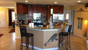A spacious kitchen with a central island, wooden cabinets, and stainless steel appliances. - Luxurious Waterfront Holiday Home with Fully Encompassing Lakeview  (Holiday)