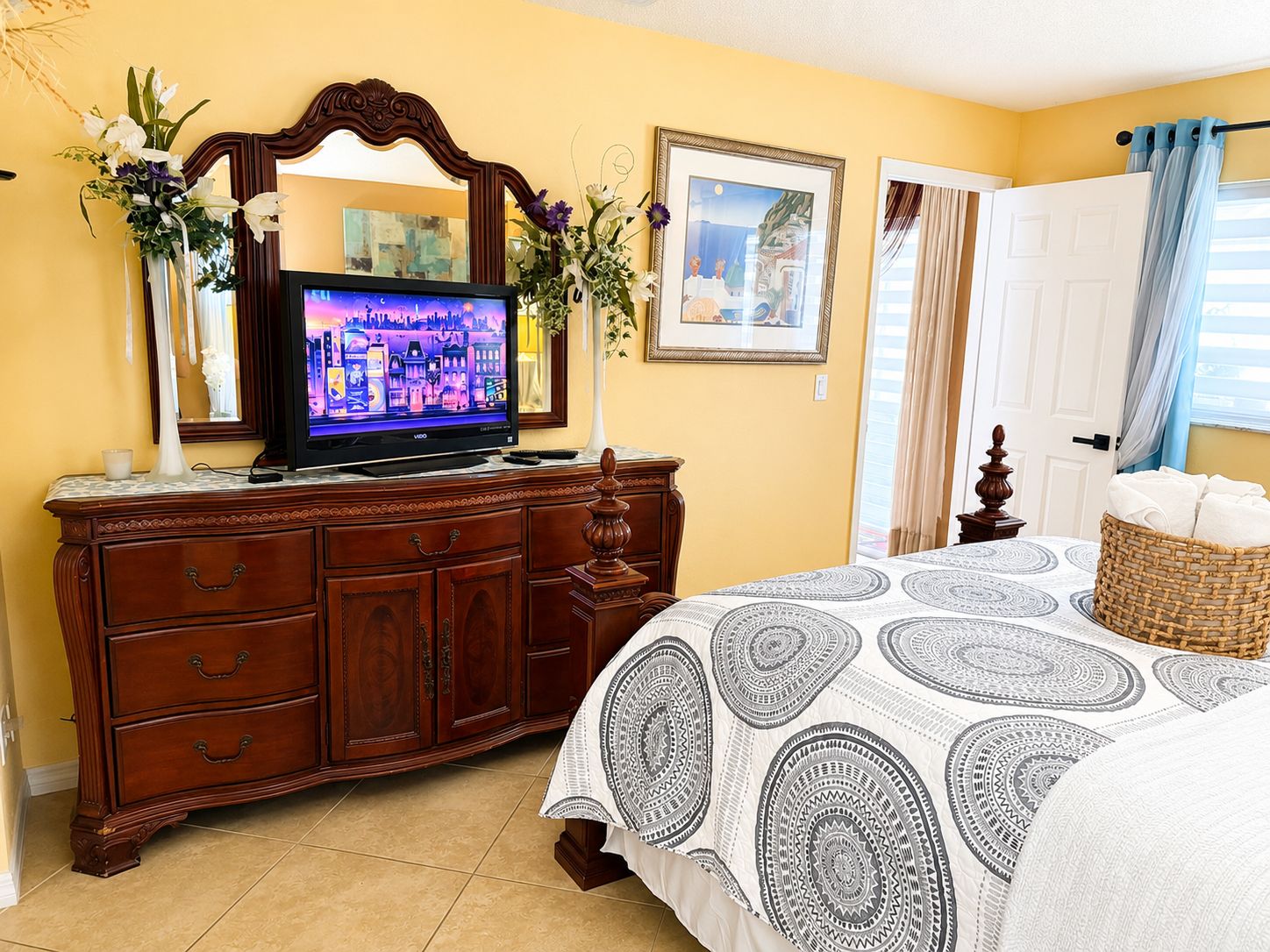 Un dormitorio con televisión, cómoda, cama y obras de arte.