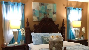 A bedroom with a wooden bed, two nightstands with lamps, a decorative basket, and a painting on the wall. - Luxurious Waterfront Holiday Home with Fully Encompassing Lakeview  (Holiday)