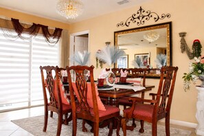 A dining room with a large mirror, ornate chairs, and a chandelier.