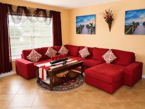 A living room with a red sectional sofa, a coffee table, and a large window with curtains. - Luxurious Waterfront Holiday Home with Fully Encompassing Lakeview (Holiday)