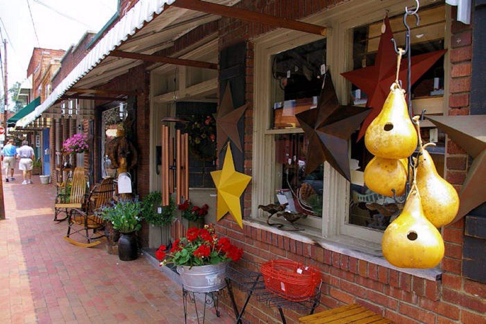 A storefront with a brick facade, large windows, and various hanging decorations including stars and gourds.