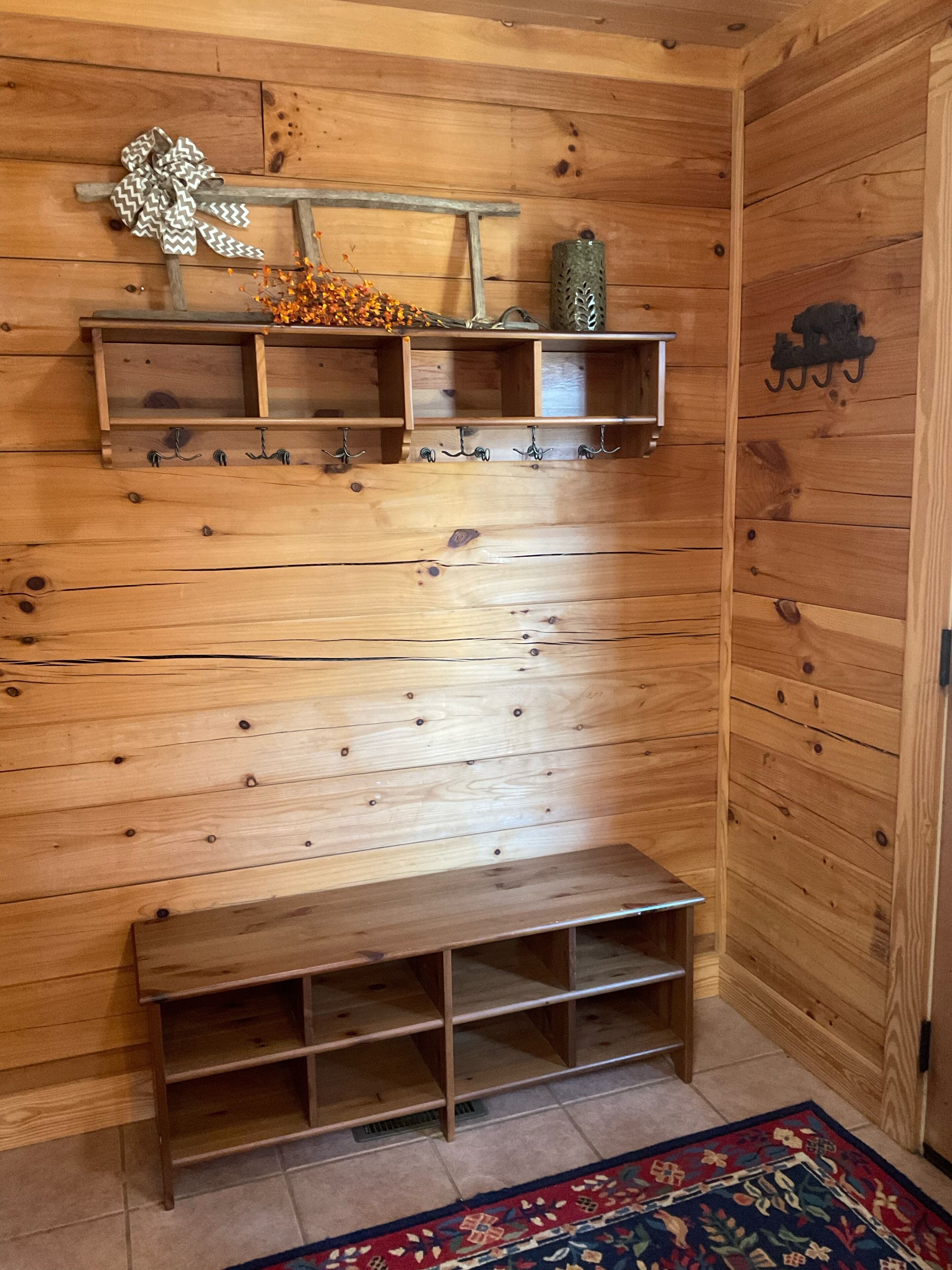 A wooden wall with a bench, shelves, and hooks.