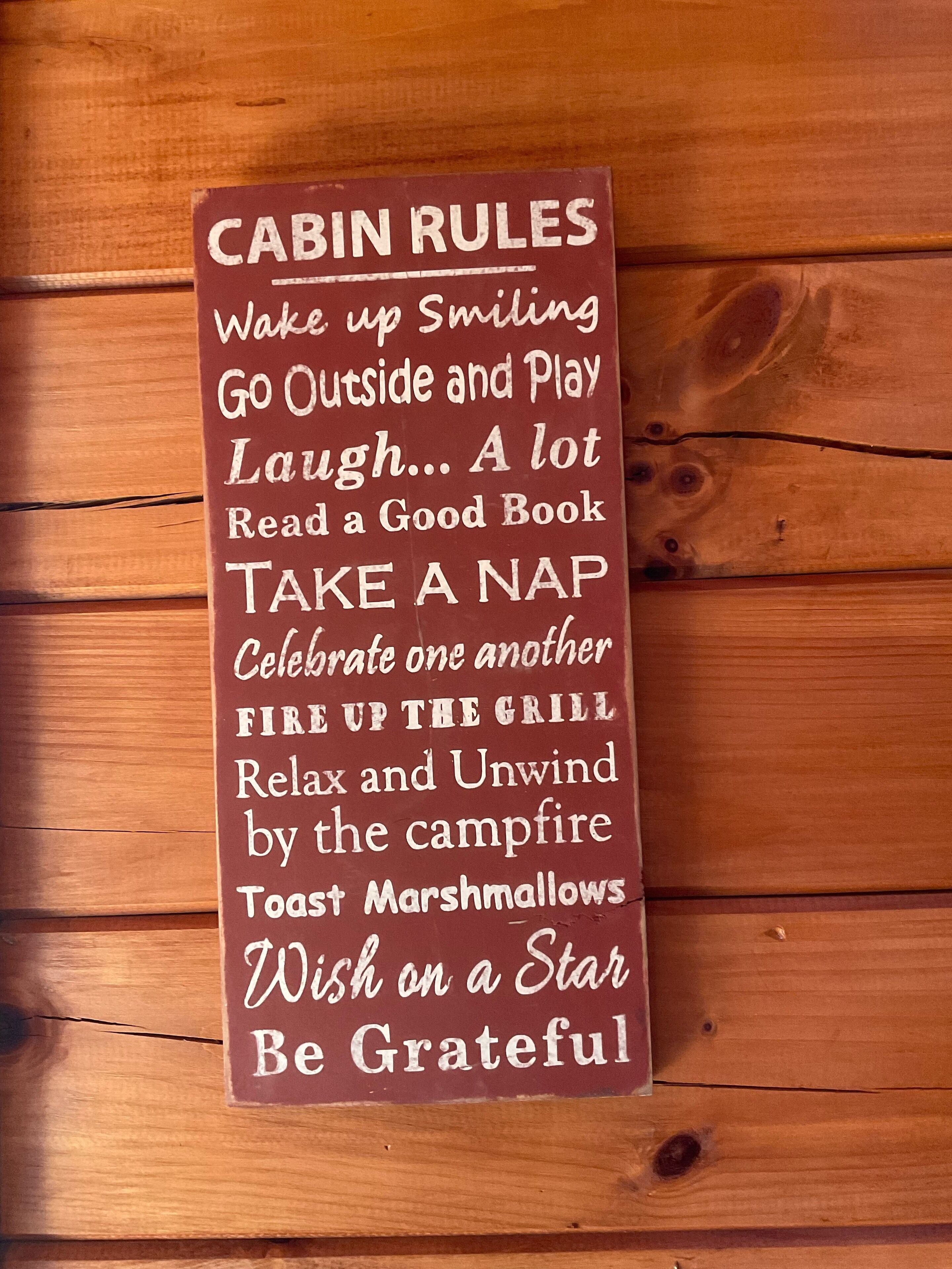 A wooden sign with cabin rules listed on it.