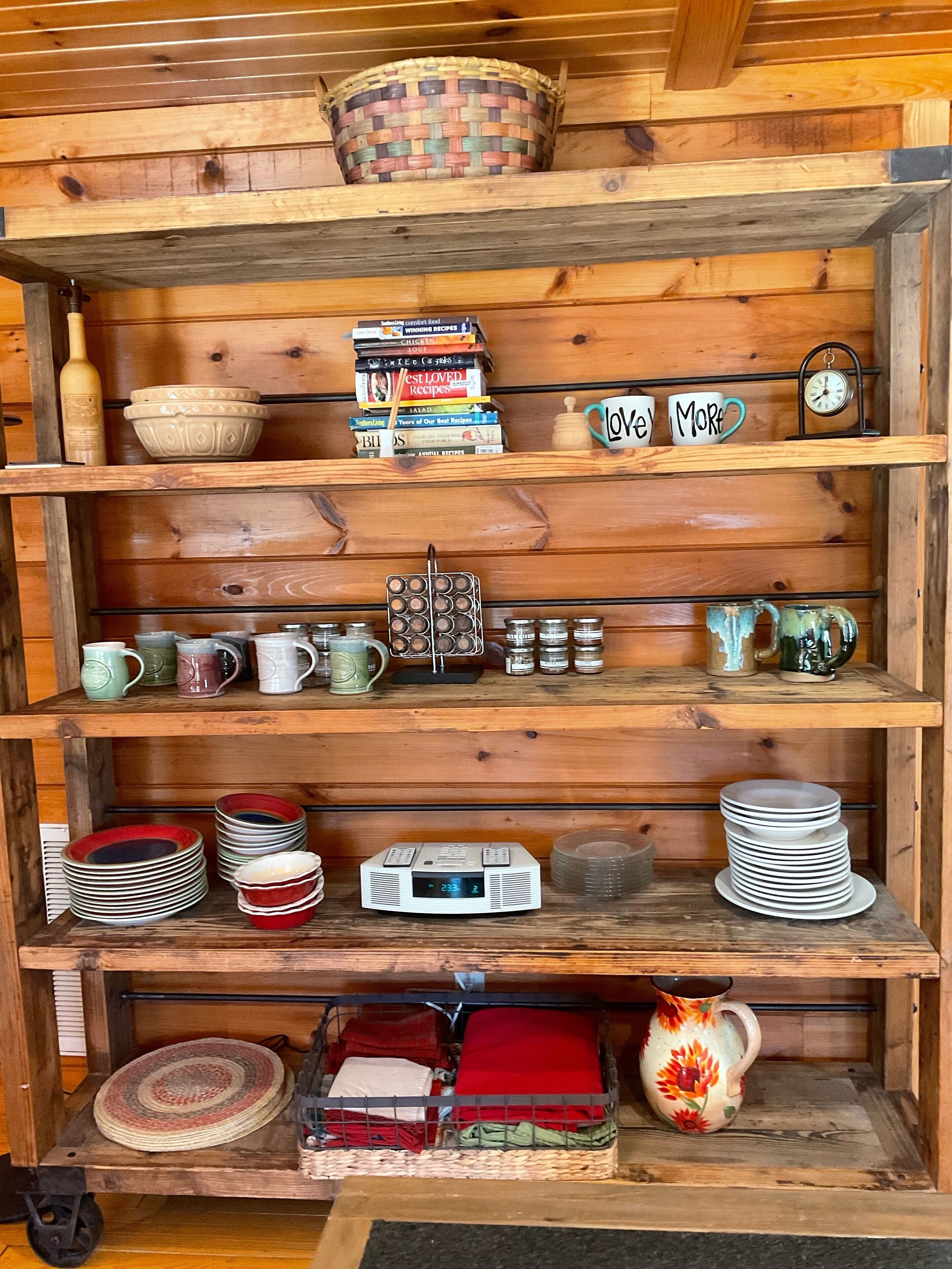 Ein Regal aus Holz mit diversen Küchenutensilien und Büchern.