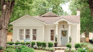 A single-story house with a front porch, a small garden with various plants and flowers, and a mailbox. - Historic Southern Cottage close to Downtown Conway (Conway)