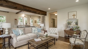 A spacious living room with a sofa, armchairs, a coffee table, and a dining area with a wooden table and chairs. - Historic Southern Cottage close to Downtown Conway (Conway)