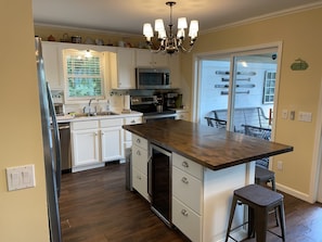 A kitchen with white cabinets, a central island, stainless steel appliances, and a chandelier. - Large Barn styled vacation home that fits groups with space to spare.   (Craryville)