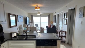 A modern kitchen with a dishwasher, a dining area with chairs, a ceiling fan, and a view to the outside. - Reduced rates!!  A+ Spectacular Beach Front Condo! 2BR 2BA!  Sleeps up to 6. (Orange Beach)