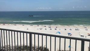 A beach with a ship in the water, umbrellas, and people on the sand. - Reduced rates!!  A+ Spectacular Beach Front Condo! 2BR 2BA!  Sleeps up to 6. (Orange Beach)