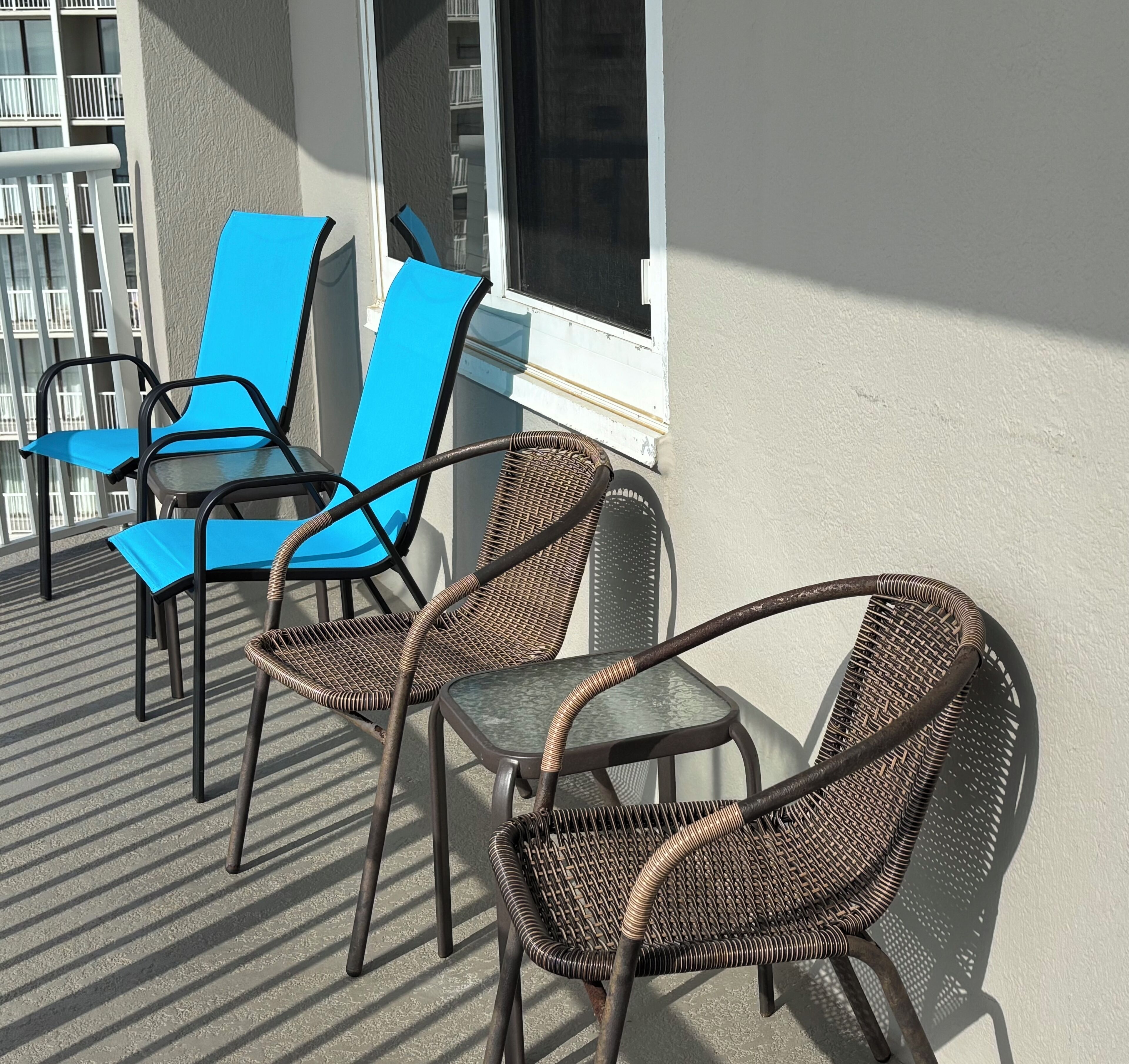 Un balcone con sedie in vimini e una sedia blu.