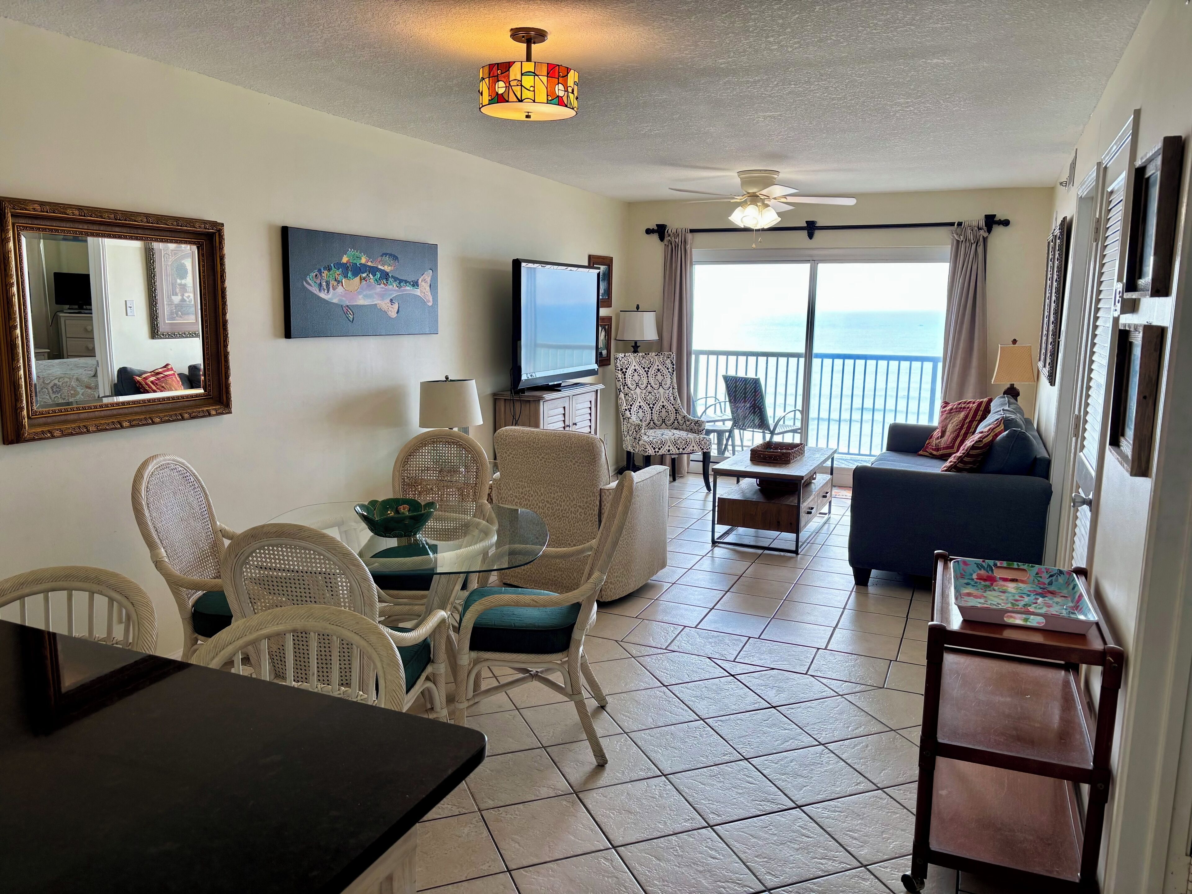 A living room with a dining area, a TV, and a balcony with a view.