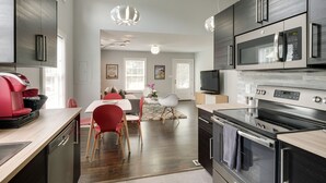 Una cucina moderna con forno, microonde ed elettrodomestici inclusi. C'è un'area pranzo con tavolo e sedie.