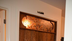 A hallway with a wooden door, a decorative wall with a mosaic, and a carpeted floor.