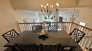 A dining area with a dark wooden table, black chairs, and a chandelier. - Luxury condo steps away from Siesta Key public beach  (Siesta Key)