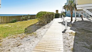 A wooden pathway leading to a beachside property with a clear view of the ocean.