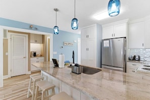 Una cocina moderna con una isla central, electrodomésticos de acero inoxidable e iluminación colgante.