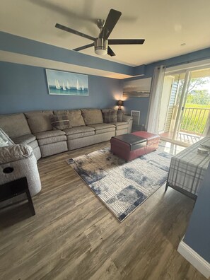 A living room with a ceiling fan, a sofa, a coffee table, a rug, and a view through a glass door. - Now renting summer of 2027 (Hampton)