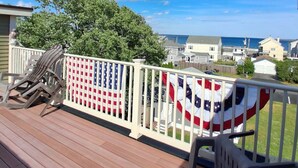 Une terrasse en bois avec une rambarde, deux chaises et un drapeau américain.
