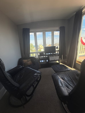 Ein Wohnzimmer mit Sofa, Sessel, einem kleinen Tisch und Meerblick durch große Fenster.
