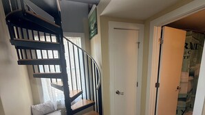 Une pièce avec un escalier en colimaçon, une porte blanche et un banc.