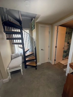 Ein Zimmer mit einer Wendeltreppe, einer weißen Tür und einer Bank.