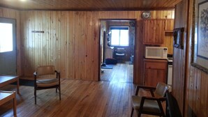 A wooden-paneled room with a ceiling fan, a microwave, and a framed picture on the wall.
