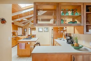 A spacious kitchen with wooden cabinets, a central island, and a hanging light fixture.